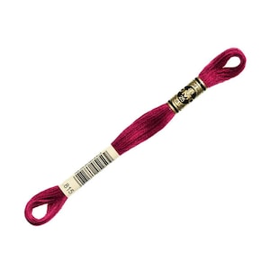 May include: A single skein of DMC embroidery floss in a deep magenta color. The floss is wrapped and labeled with the number 815. The label also includes the DMC logo and other product information.