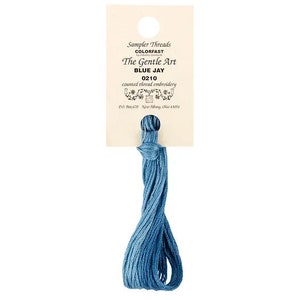 May include: A skein of blue embroidery floss labeled "Sampler Threads Colorfast The Gentle Art Blue Jay 0210 counted thread embroidery"