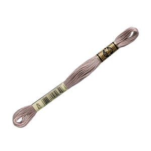 May include: A single skein of DMC 25 embroidery floss in a muted mauve color. The label displays the number 452, a barcode, and the DMC logo. The floss is tightly wound and ready for use in cross-stitch, embroidery, or other needlework projects.