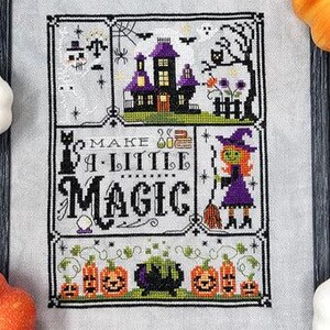 May include: Cross stitch pattern featuring a witch, a haunted house, pumpkins, and the text "Make a Little Magic".