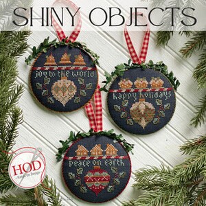 Può includere: Tre ornamenti natalizi rotondi con sfondo blu e lettere bianche. Gli ornamenti presentano le frasi "Joy to the World", "Happy Holidays" e "Peace on Earth". Ogni ornamento è decorato con una ghirlanda di foglie verdi e un nastro rosso.