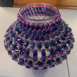 Beaded candle holder with light and dark blues, light and dark lavenders and pale yellows.