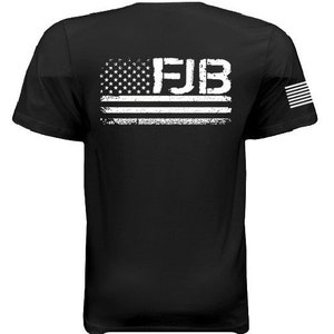 May include: Black t-shirt with a white distressed American flag and the text "FJB" on the back. The shirt also has a small American flag on the right sleeve.