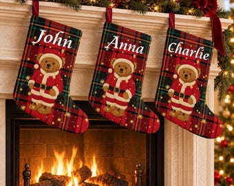 May include: Three Christmas stockings featuring a red and green plaid pattern with gold star accents. Each stocking displays a teddy bear wearing a Santa suit and a name printed in white script: John, Anna, and Charlie, hanging from a mantel.
