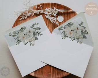 Pode incluir: Dois envelopes brancos com um design floral na aba. O design apresenta flores brancas e folhas verdes sobre um fundo azul claro.