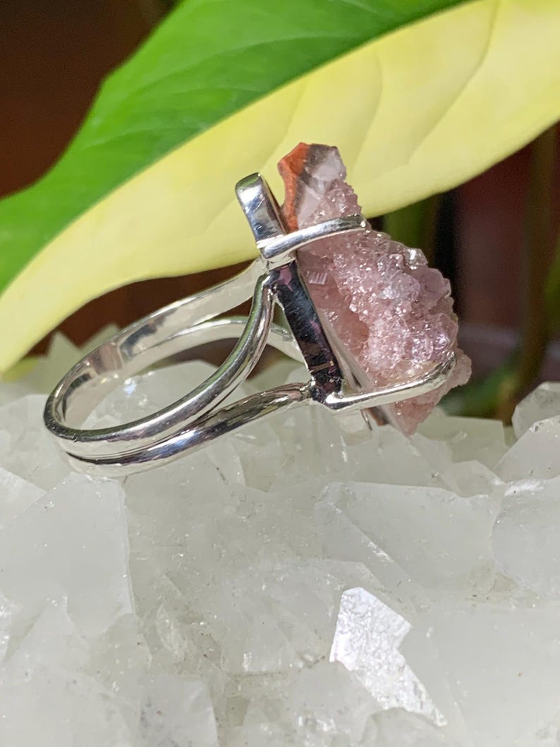 K&ouml;nnte beinhalten: Ein silberner Ring mit einem pinkfarbenen und roten Kristall in der Mitte. Der Kristall ist ein Cluster aus kleinen Kristallen.