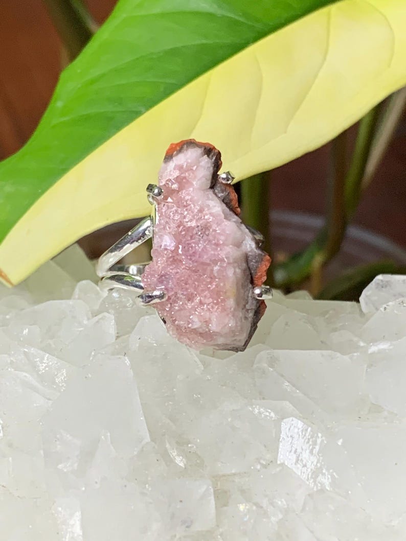 K&ouml;nnte beinhalten: Ein silberner Ring mit einem rosa und orangefarbenen Kristall. Der Kristall ist ein Cluster aus kleinen Kristallen.