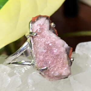 K&ouml;nnte beinhalten: Ein silberner Ring mit einem rosafarbenen und roten Kristall in der Mitte. Der Kristall ist rau und hat eine nat&uuml;rliche, organische Form.