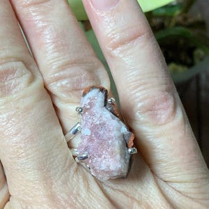 K&ouml;nnte beinhalten: Ein silberner Ring mit einem rosafarbenen und wei&szlig;en Kristallstein. Der Stein ist ein Cluster aus kleinen Kristallen mit einer rauen, nat&uuml;rlichen Textur.