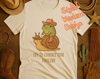 Rustik Cowboy Groda T-shirt – “Off to Commit Tomfoolery” Rolig Cottagecore Snail Rider T-shirt.