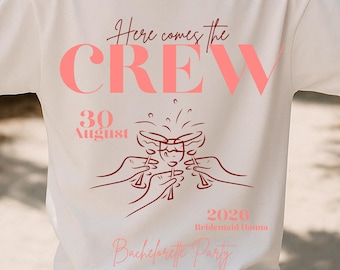 May include: White t-shirt with the text "Here comes the CREW" in pink, along with "30 August 2020" and "Bachelorette Party" in pink script. The design includes illustrations of hands toasting with glasses.