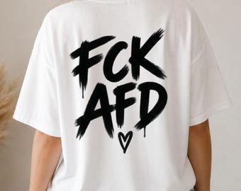 May include: A white short-sleeved t-shirt featuring a large black graphic on the back. The design consists of the text FCK AFD written in a bold, brush-stroke style with a dripping paint effect, accompanied by a small black heart symbol below.