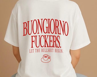 May include: A white short-sleeved t-shirt featuring red text on the back that reads BUONGIORNO FUCKERS. LET THE BULLSHIT BEGIN. Below the text is a simple red line drawing of a coffee cup on a saucer, centered on the back of the garment.