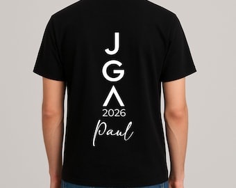 May include: Black t-shirt with white text on the back. The text includes the letters "JGA", the number "2026", and the name "Paul" in a cursive font. The shirt is short-sleeved.