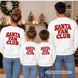 May include: Four white crewneck sweatshirts featuring the red text SANTA FAN CLUB printed on the back. The garments are worn by two adults and two children, all paired with blue denim jeans, showcasing a matching set of long-sleeved tops.