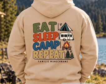 May include: A beige hooded sweatshirt featuring a graphic on the back with the text EAT SLEEP CAMP REPEAT. The design includes a tent, a camper trailer, a campfire, and two pine trees. Below the text is the phrase FAMILIE WUNSCHNAME.