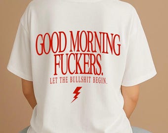 May include: A white short-sleeved t-shirt featuring red text on the back that reads GOOD MORNING FUCKERS. LET THE BULLSHIT BEGIN. Below the text is a small red lightning bolt graphic. The shirt has a crew neckline and a standard fit.