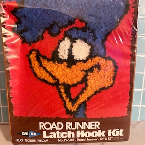 May include: A Road Runner latch hook kit featuring a cartoon image of the Road Runner character. The kit includes a rug, picture, and pillow design. The finished size is approximately 12 inches by 12 inches.