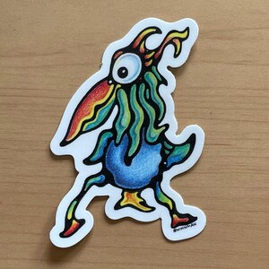 May include: A colorful cartoon bird sticker with a blue body, green and yellow feathers, and a red and yellow beak. The bird has a large, white eye and is walking with its legs outstretched. The sticker is signed "WINNMAN".