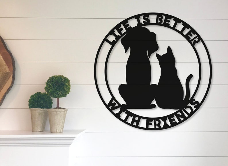 May include: Black metal wall decor with a dog and cat silhouette inside a circle. The text "Life is better with friends" is written around the circle.