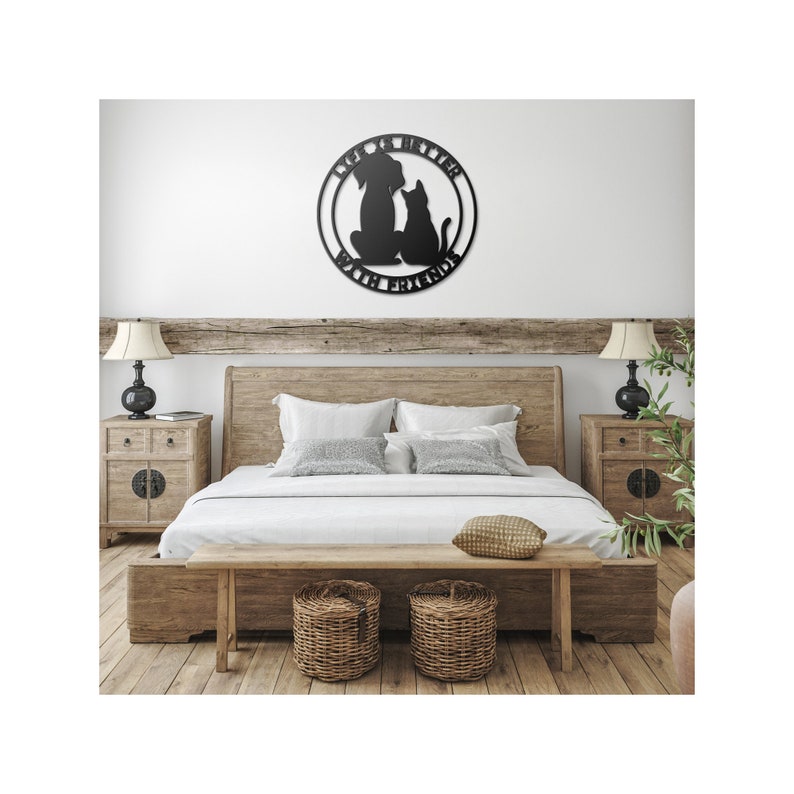 May include: Black metal wall art featuring a dog and cat silhouette with the text "Life is better with friends". The art is hanging on a white wall above a wooden bed frame with white bedding.