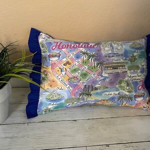 May include: A blue and white pillow with a map of Honolulu, Hawaii. The pillow has a blue ruffle trim and features landmarks like Ala Moana Blvd, Fort St, and the Hawaii State Capitol.