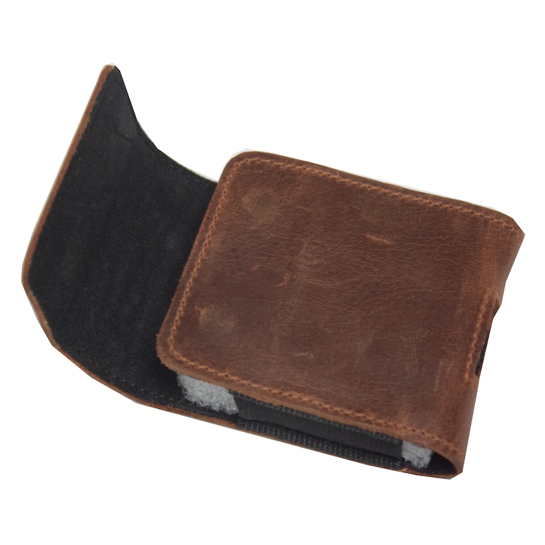 May include: A brown leather wallet with a distressed finish. The wallet is open, revealing a black interior and a gray lining. The leather has a textured appearance, and the stitching is visible around the edges.