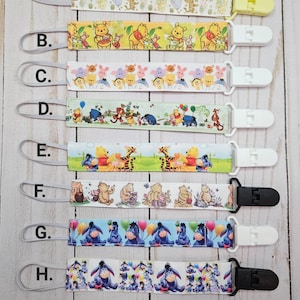 May include: Eight colorful fabric baby teethers with different cartoon characters. The teethers are attached to a white plastic clip. The teethers are labeled A through H.