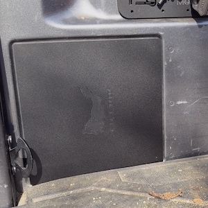May include: A black plastic panel with a cutout of a rabbit and the word "BRAVO" printed vertically. The panel is attached to a gray surface.