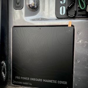 May include: Black metal magnetic cover with a topographic map design and the text "PRO POWER ONBOARD MAGNETIC COVER BUCKING RABBIT CO."