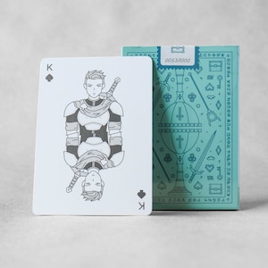May include: A playing card with a black spade suit and the letter K. The card features a black and white illustration of a knight in armor with a sword and a shield. The card is part of a deck of playing cards with a blue and white design.