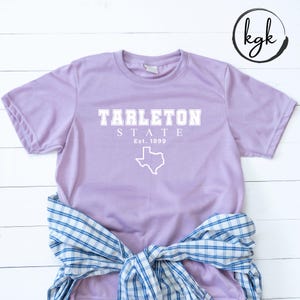 May include: A lavender t-shirt with a white graphic that says "Tarleton State Est. 1899" and a white outline of the state of Texas.