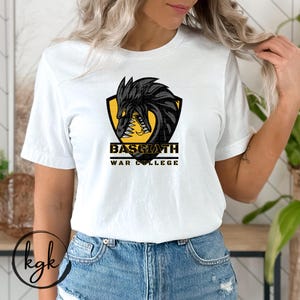 May include: White t-shirt with a black and yellow graphic of a dragon's head with the text "Basgiath War College".