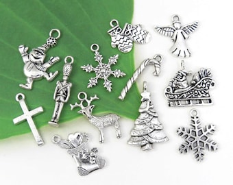 May include: A collection of silver-toned Christmas charms, including a snowman, snowflake, angel, Santa in a sleigh, and a Christmas tree. Other charms include a cross, a soldier, a reindeer, a stocking, a pair of mittens, and a candy cane.