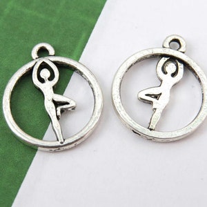 May include: Two silver charm pendants featuring a yoga pose in a circle. The charms are perfect for jewelry making or adding a touch of spirituality to your crafts.