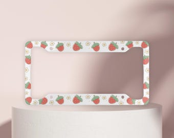 May include: White metal license plate frame with a border of red strawberries and yellow flowers.