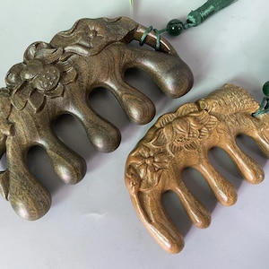 Puede incluir: Dos peines de madera con intrincadas tallas florales. Los peines son de color marrón oscuro, con un acabado liso y pulido. Cada peine tiene un mango con una borla y una pequeña cuenta verde. Los peines están diseñados para el cuidado del cabello.