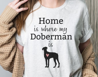 May include: A gray t-shirt with the text "Home is where my Doberman is" and a black silhouette of a Doberman with a pink heart on its chest.
