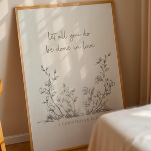 Può includere: Una stampa artistica rettangolare in una cornice di legno chiaro con il testo "let all you do be done in love" in un carattere corsivo scuro, con un disegno botanico a linee di fiori sotto e il testo "1 CORINTHIANS 16:14" in basso.