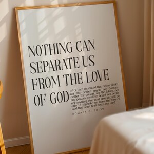 Op de afbeelding: Een rechthoekige wandkunstprint in een lichthouten lijst met zwarte tekst op een witte achtergrond. De tekst luidt: NOTHING CAN SEPARATE US FROM THE LOVE OF GOD, gevolgd door de volledige bijbeltekst Romeinen 8:38-39 in een kleiner lettertype.