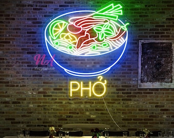May include: A neon sign depicting a bowl of pho, with blue, green, red, and yellow lights. The word "PHO" is illuminated in yellow below the bowl. The sign is mounted on a brick wall above a dining table.