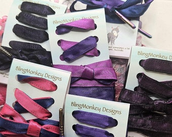 May include: Assortment of hair accessories from Bling Monkey Designs. The image showcases various hair ties and bows in shades of purple, pink, and navy blue. Each set is displayed on a card with the brand's logo and text. The accessories are made with love in Brisbane, Australia.