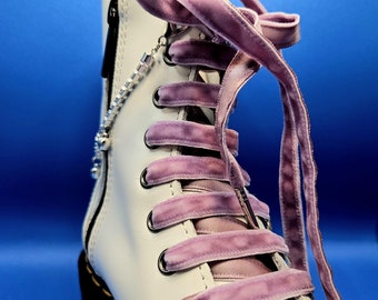 May include: White leather ankle boots with a zipper on the side and purple velvet laces. The laces are tied in a bow at the top of the boot.