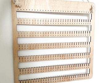 Könnte beinhalten: Holz-Ohrringhalter mit fünf Reihen Löchern zum Aufbewahren von Ohrringen. Der Halter ist aus hellbraunem Holz und hat ein Seil zum Aufhängen.
