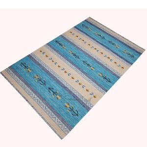 Handwoven kilim wool rug in blue and beige with tribal geometric motifs and border—flatweave carpet, boho decor.
