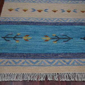 Handwoven kilim rug in blue and beige with tribal geometric motifs and fringe; flatweave carpet for boho ethnic decor.