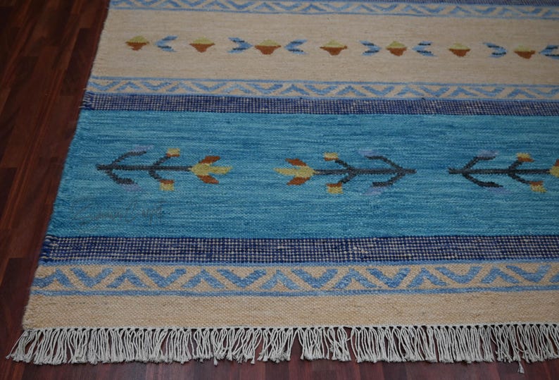 Handwoven kilim rug in blue and beige with tribal geometric motifs and fringe; flatweave carpet for boho ethnic decor.