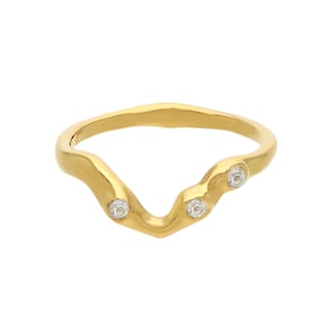 May include: A gold ring with a wavy band and three small clear stones.