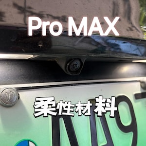 以下が含まれることがあります： 後ろに「Pro MAX」と書かれた黒い車。車にはバックカメラと「柔軟材料」と書かれたナンバープレートが付いています。
