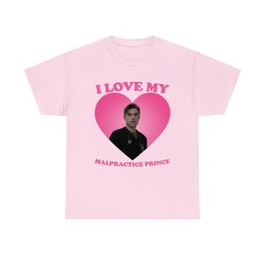 Puede incluir: Camiseta rosa claro con el texto "I LOVE MY" sobre un corazón rosa que contiene a un hombre con una camisa negra. Debajo del corazón está el texto "MALPRACTICE PRINCE".
